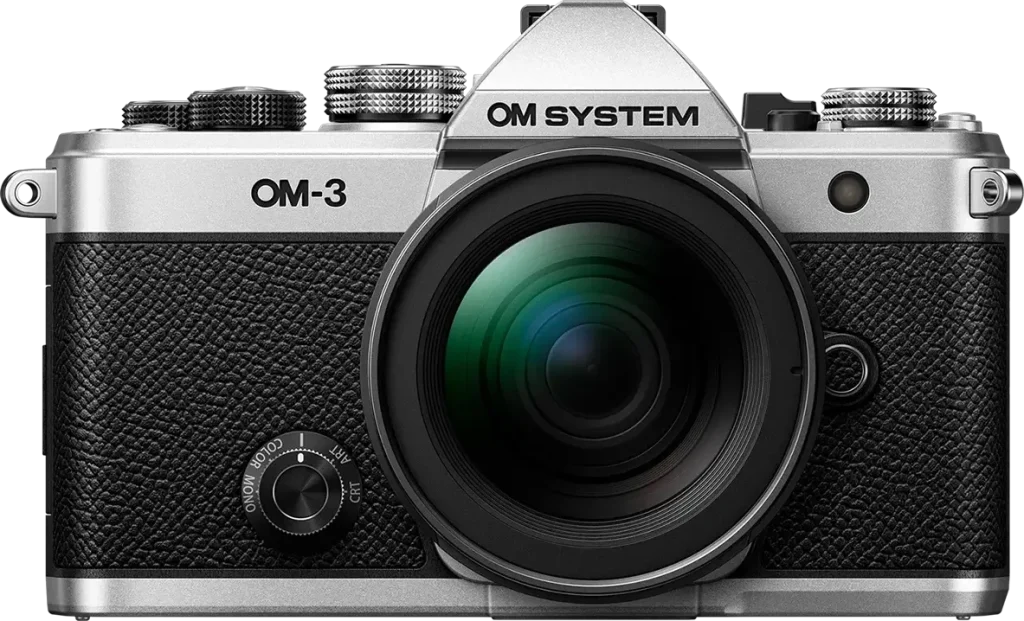 OM System OM-3 mit Kreativ-Wahlrad und Objektiv vor weißem Hintergrund